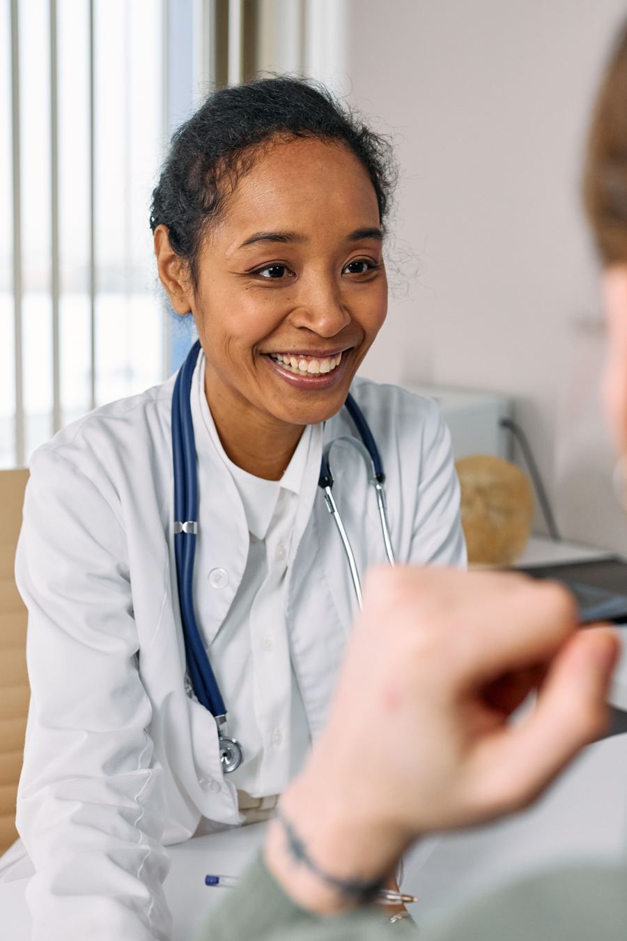 A smiling Medicentres family physician in a white coat talks with a patient